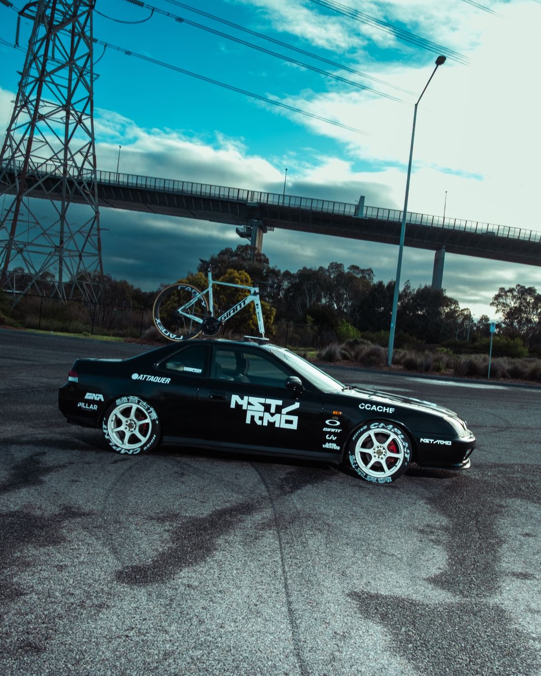 The NSTRMO team car side-on under the bridge and power lines
