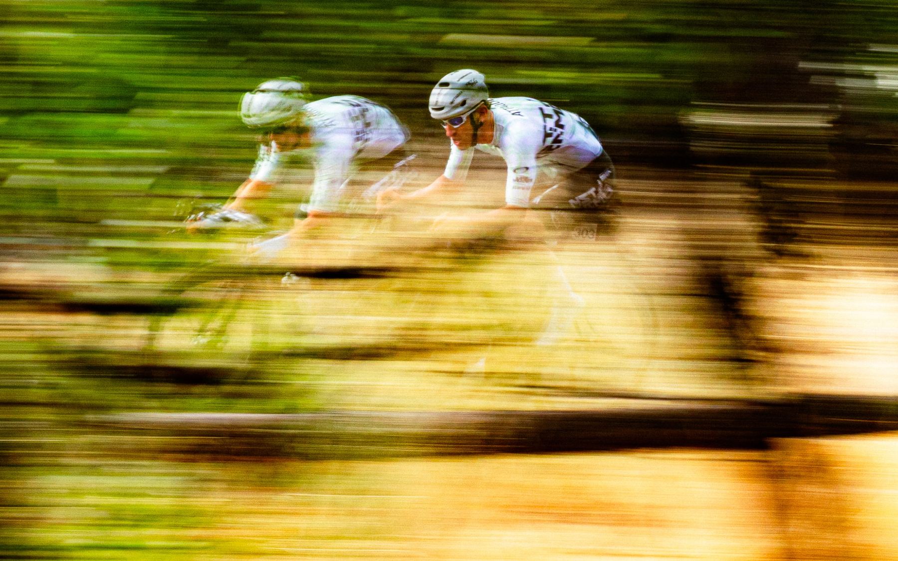 Two NSTRMO riders at speed, green and gold blur